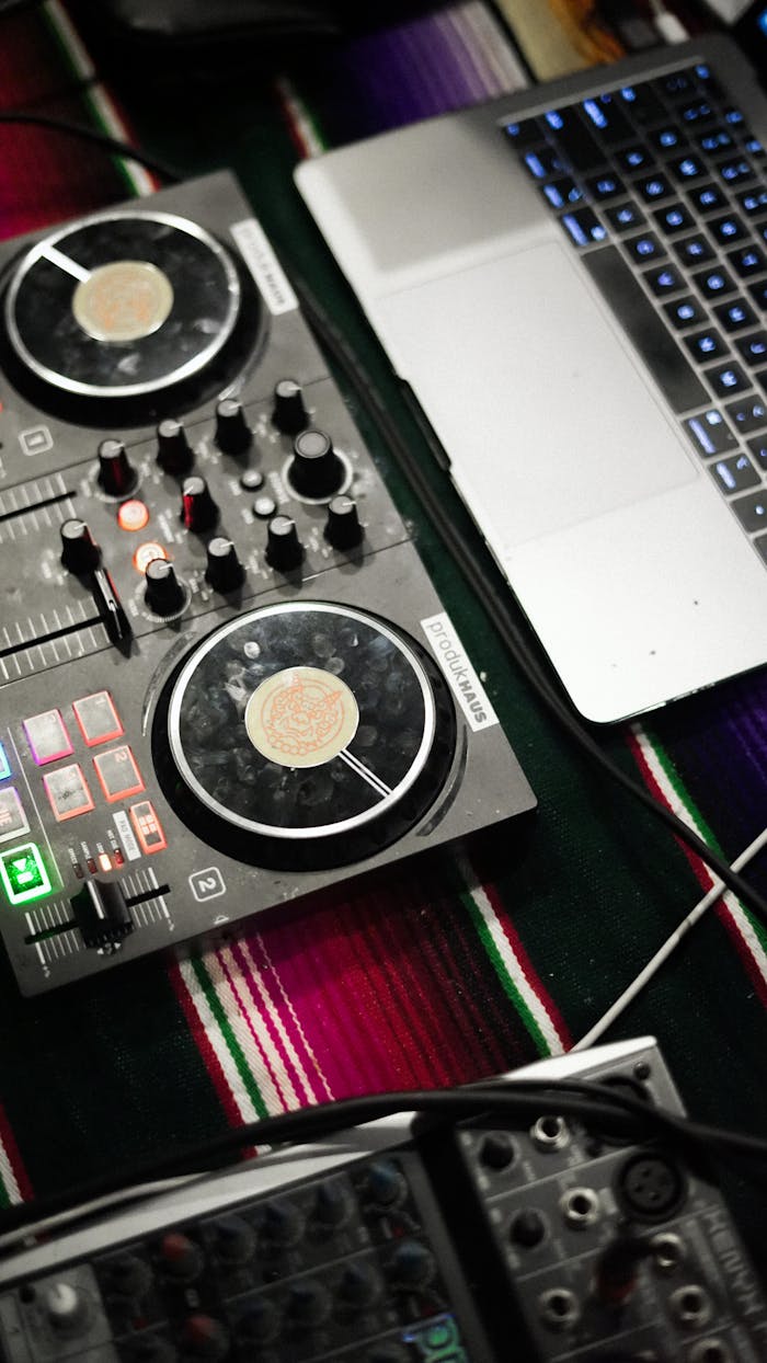 A DJ mixer and laptop on a vibrant textile, showcasing music technology setup.